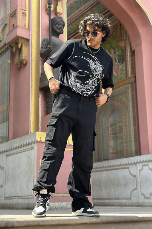 A pair of black Ronazen Transformer Urban Cargo Pants featuring a modular, multi-pocket design with the ability to transform into shorts. The fabric is durable and the pants have a tactical aesthetic with utility loops and adjustable straps for a customizable fit. These cargo pants are designed for urban environments and versatile outdoor activities, providing both functionality and style
