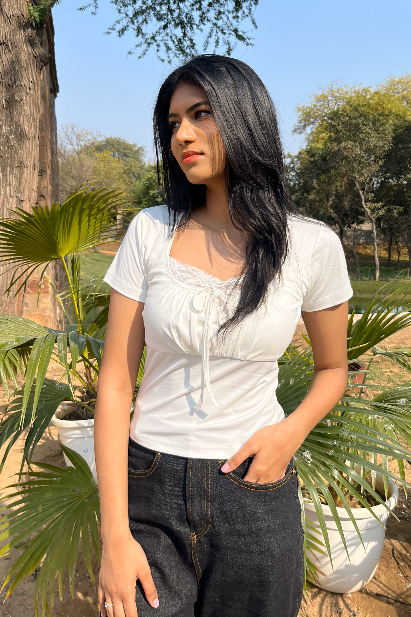 A delicate, lace-trimmed white top by Ronazen, featuring intricate lace detailing along the neckline and sleeves. The top is made from a light, breathable fabric, ideal for a graceful, feminine look. The lace trim adds a touch of elegance, making it suitable for both casual and more formal occasions. The design is simple yet sophisticated, with a slightly fitted silhouette that flatters the figure